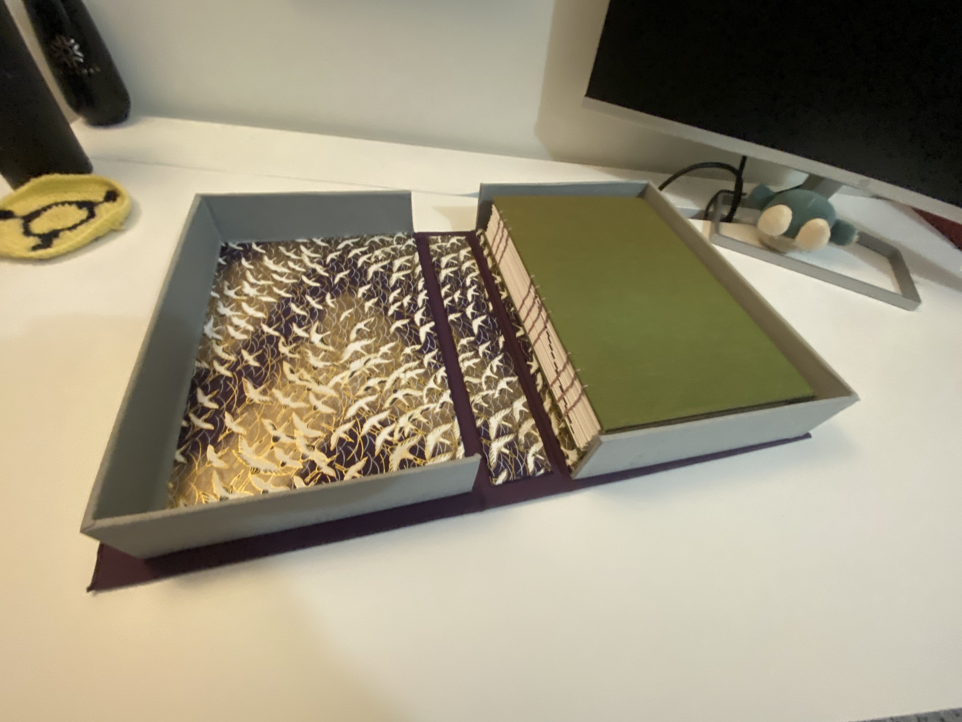 A clam-shell book box with a hard cover book inside